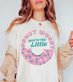 DONUT BIG LITTLE REVEAL SHIRT - BIG SISTER SHIRT We are super excited for you to get your hands on this new design Comfort Colors t-shirt. This product is very on trend and we hope you love it! 💜  If you would like to discuss any alternative size, color or product options, please do not hesitate to contact us directly. 💌 ALSO AVAILABLE AS A LITTLE SISTER SHIRT: ➡️ ➡️ ➡️ https://www.etsy.com/uk/listing/1778479587/donut-big-little-shirts-coquette ✨ ABOUT OUR COMFORT COLORS TEES ✨ These 100% ring-spun cotton unisex tees are a great staple for any wardrobe and available in various different colours. The soft-washed, garment-dyed fabric brings extra coziness to your wardrobe while the relaxed fit makes it an excellent daily choice. The double-needle stitching throughout the tee makes it highl Fun White Tops With Funny Print, Fun Tops With White Funny Print, Fun Slogan Crew Neck Top, Fun Long Sleeve Slogan T-shirt, Cute Slogan T-shirt, Cute White Print Crew Neck Top, White Long Sleeve T-shirt With Funny Text, Cute White T-shirt With Letter Print, Cute Short Sleeve Shirt With Funny Text