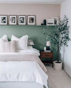 a bed with white sheets and pillows in a bedroom next to pictures on the wall