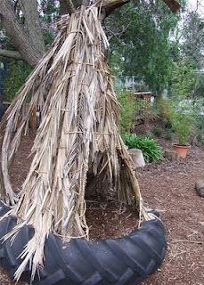 an old tire used as a shelter for a tree in a garden with lots of dry grass