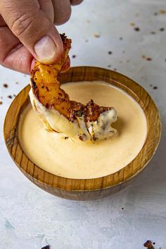 a person dipping something into a small bowl filled with sauce on top of a table