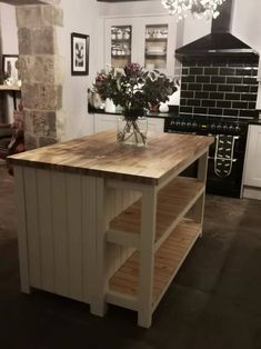 a kitchen island made out of pallets with flowers in the center and shelves on either side