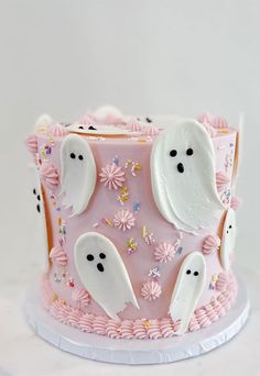 a pink cake with ghost decorations on it