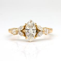 a yellow gold ring with an oval cut diamond and pear shaped diamonds on the band