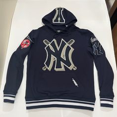 Brand - Pro Standard Item Type - Hoodie Team - New York Yankees Condition- Brand New Color - Blue, White & Grey Gender - Men’s Sizes Available; Men’s Medium Hooded Team Logo Top For Streetwear, Hooded Team Logo Streetwear Top, Hooded Tops With Team Logo For Streetwear, Sporty Team Logo Hoodie, Hooded Streetwear Tops With Team Logo, Sporty Hoodie With Team Logo, Team Spirit Tops With Drawstring Hood For Streetwear, Varsity Hooded Top For Sports Events, Blue Graphic Print Sportswear Hoodie