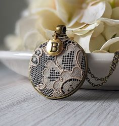 "The classic look of this lace pendant with initial charm makes it the perfect, personalized gift for her - this necklace is handmade with vintage beige lace that is actually antique in age since it's from the 1920s. It is made of cotton, as well as the black background fabric that is behind the lace. The gold and black capital letter initial charm makes this a unique way to personalize the necklace as an anniversary gift for your wife or loved one's 13 year anniversary, which is the material la Vintage Jewelry Initial Pendant For Personalized Gift, Vintage Handmade Initial Pendant Jewelry, Vintage Personalized Initial Pendant Necklace, Handmade Initial Pendant Jewelry For Wedding, Vintage Round Pendant Necklace For Personalized Gift, Vintage Round Necklaces For Personalized Gifts, Vintage Handmade Beige Jewelry, Vintage Monogram Necklace With Initial Pendant, Vintage Monogram Jewelry For Personalized Gift