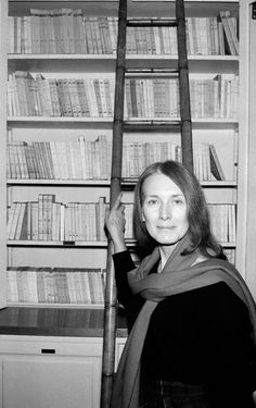 a woman standing in front of a bookshelf with a scarf around her neck