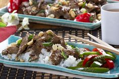 two plates filled with rice, meat and veggies next to chopsticks