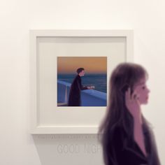 a woman talks on her cell phone in front of a painting