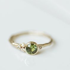 a close up of a ring with a green stone in the middle and two diamonds on each side