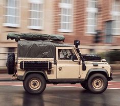 an off - road vehicle driving down the street in front of a large brick building