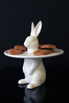 a white bunny sitting on top of a plate filled with cookies