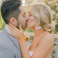 a bride and groom kissing each other outside