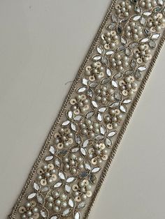 a close up of a ribbon with pearls and beads on it's side,