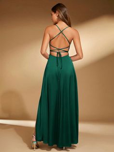 the back of a woman wearing a long green dress with straps on her shoulders and an open neckline