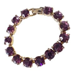 This vintage women's tennis bracelet showcases a 14+ carat purple amethyst gemstone, which has been lab-created and is perfectly round in shape. The gemstone is set in a gold tone metal with slight signs of wear, stone with minor loss,, but is still in overall good condition. Measuring 6.75 inches in length and 0.25 inches in height. Purple Jewelry With Jubilee Bracelet For Anniversary, Purple Round Bracelets For Anniversary, Purple Round Stone Jewelry For Formal Occasions, Purple Tennis Bracelet For Anniversary, Classic Amethyst Bracelets In Purple, Classic Amethyst Purple Bracelets, Purple Round Tennis Bracelet For Formal Occasions, Classic Purple Tennis Bracelet As A Gift, Classic Purple Amethyst Bracelets