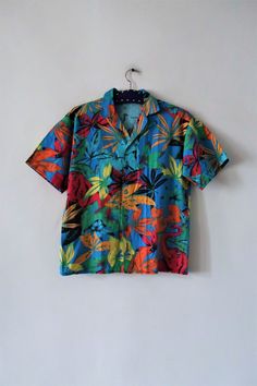 Stunning Vintage Hawaiian style shirt from the 1980s. Comfortable cotton fabric with an amazing tropical jungle print featuring elephants and exotic plants. Straight cut, short lapel collar, short sleeves. Button down. Unisex. Made in Italy! Wear oversized and combine with Bermudas and sandals. BRAND: Marc Aurel ERA: 1980s COLOR: Azure blue, turquoise, green, raspberry, orange, yellow, brown, black FABRIC: 100% cotton SIZE: Vintage size S, fits best men's size S or woman's size M (or S for a mor Cheap Retro Green Hawaiian Shirt, Cheap Green Hawaiian Shirt, Multicolor Cotton Hawaiian Shirt For Summer, Summer Multicolor Cotton Hawaiian Shirt, Multicolor Cotton Hawaiian Summer Shirt, Multicolor Collared Shirt With Tropical Print, Multicolor Collared Hawaiian Shirt With Floral Print, Summer Multicolor Hawaiian Shirt With Camp Collar, Multicolor Tropical Cotton Camp Shirt