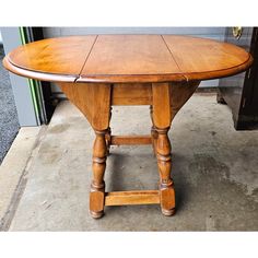 an oval wooden table sitting on top of a cement floor next to a doorway and door