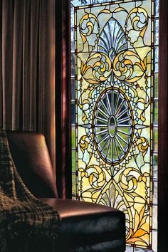 a chair sitting in front of a stained glass window with an ornate design on it