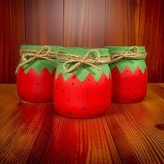 three jars with strawberries painted on them