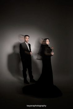 a man and woman standing next to each other in front of a wall with shadows on it