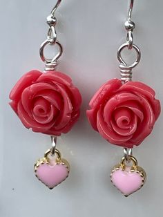 These serene Coral Rose Earrings are as soothing as the oceans waves. 14mm coral polyresin rose beads accented with a 8mm light pink heart charm. All hand wire wrapped in silver plated wire. 1.75 inches long. Let the coral reefs beckon to you. Pink Rose Design Flower Earrings For Valentine's Day, Pink Rose Design Jewelry For Valentine's Day, Hypoallergenic Pink Sterling Silver Heart Earrings, Hypoallergenic Pink Heart Earrings In Sterling Silver, Sterling Silver Jewelry With Pink Flower Charm, Pink Rose Design Earrings For Valentine's Day, Pink Flower Charm Dangle Jewelry, Coral Jewelry Gift With Ear Wire, Pink Dangle Jewelry With Rose Design