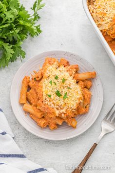 a white plate topped with pasta covered in sauce and parmesan cheese next to a fork