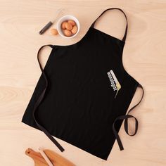 an apron and wooden utensils sit on a table next to a bowl of eggs