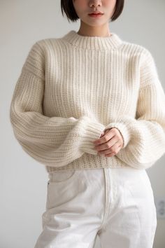 a woman wearing white pants and a sweater