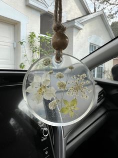 an air freshener hanging from the dashboard of a car with flowers on it and a vase