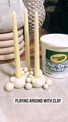 some candles are sitting on a table with white balls in front of them and the words playing around with clay