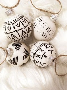 three white ornaments with black designs on them sitting on a fur covered floor next to some string