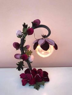 a vase filled with flowers sitting on top of a white table next to a light