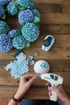 a person is decorating flowers with blue and white decorations on a wooden table next to an ironing board