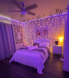 a bedroom decorated in purple and white with fairy lights