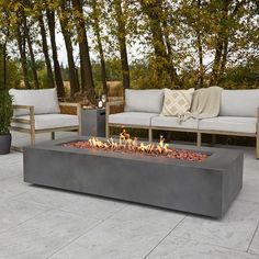 a fire pit sitting on top of a patio next to two couches and trees