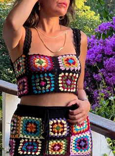 a woman wearing a crochet top and shorts with her hand on her head