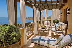 an outdoor covered patio with chairs and curtains