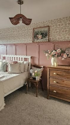 a bed room with a neatly made bed next to a dresser and flowers on the wall