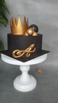 a black and gold cake on a white pedestal