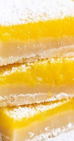 three slices of lemon bars are stacked on top of each other with powdered sugar