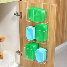 three plastic containers are attached to the wall in front of a wooden cabinet with plates and cups on it