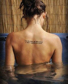 a woman with a tattoo on her back sitting in the water