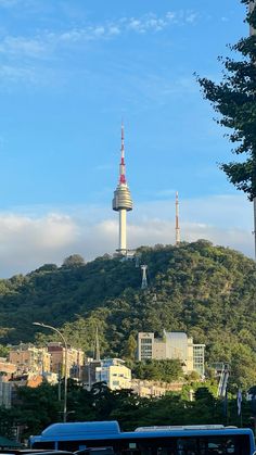 a blue bus driving past a tall building on top of a hill