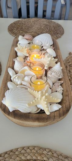 a tray with candles and seashells on it sitting on top of a table