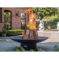 a fire pit sitting on top of a cement slab in front of a statue and trees