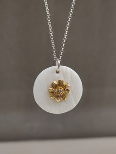 "This pendant necklace is made of white matte porcelain, the pendant is round and the surface is embossed, the center of the pendant is decorated with a silver gilded  flower which decorates it in the center a round zircon. The pendant is passed on a silver chain, with a handmade silver hook. It has a minimal design and is suitable for a casual elegant look. There may be a slight difference between the pieces, because they are all produced handmade one by one. The porcelain is left matte, in its natural texture , without any use of enamel and glazing, highlighting its beauty and its properties. Each piece is hand shaped by me before being fired in a kiln to 1240C. Important Note: The oxidization will gradually wear off eventually, depending on use, the chain will get a sort of a vintage lo Elegant White Round Disc Jewelry, White Flower Charm Round Pendant Jewelry, White Round Pendant Jewelry With Flower Charm, White Pendant Necklace With Flower Charm, White Flower Charm Pendant Jewelry, White Sterling Silver Medallion Jewelry, White Medallion Jewelry Gift, White Medallion Necklace For Anniversary, White Engraved Round Pendant Jewelry