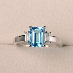 a ring with an aqua blue topazte and two white diamonds on the side