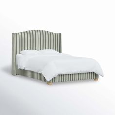 an upholstered bed with white sheets and green striped headboard