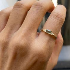 a person's hand with a gold ring on it and a diamond in the middle