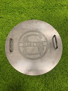 a metal plate sitting on top of a green grass covered field with the word's logo